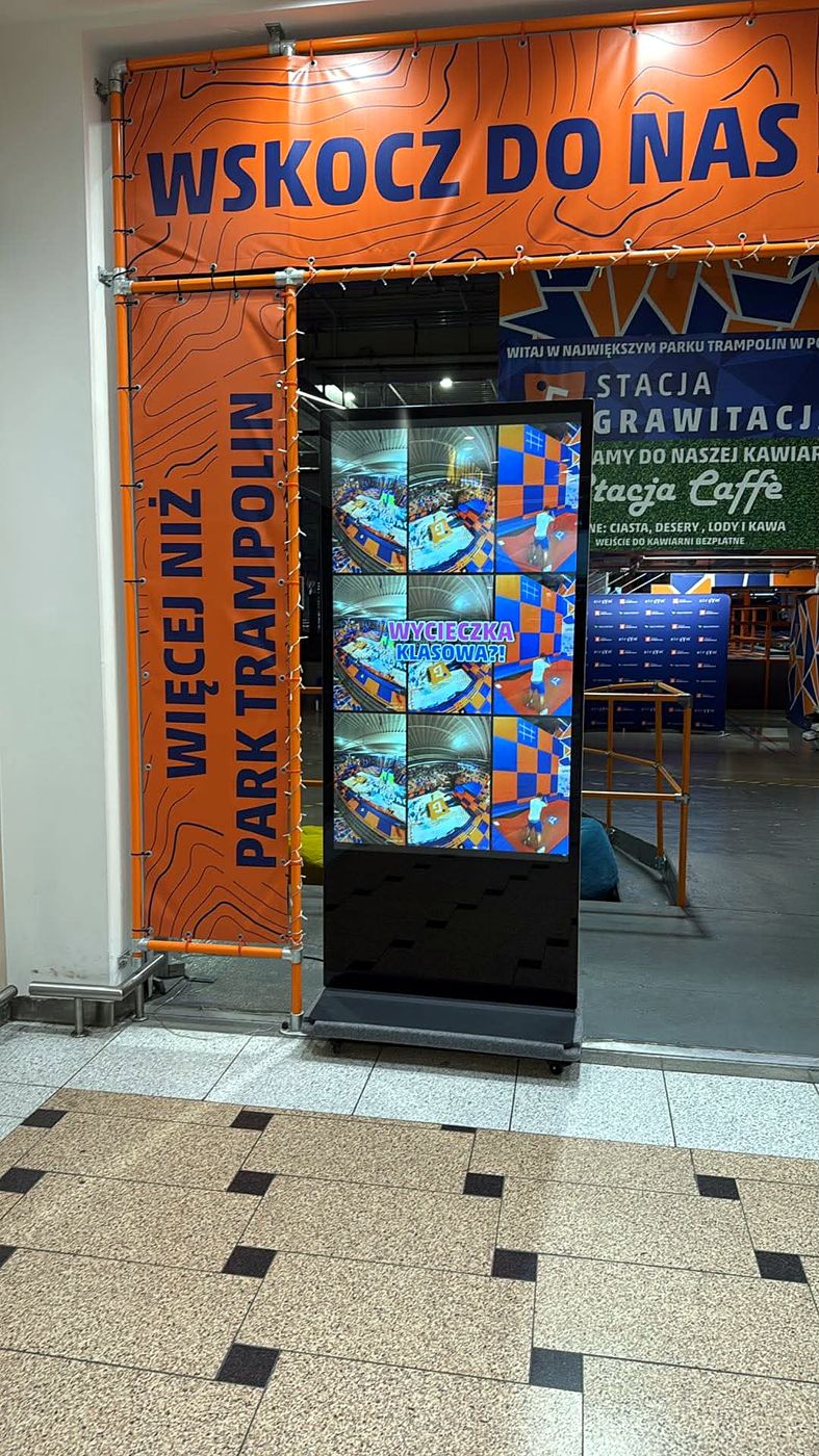 Telewizor 65" pionowy przy wejściu z galerii